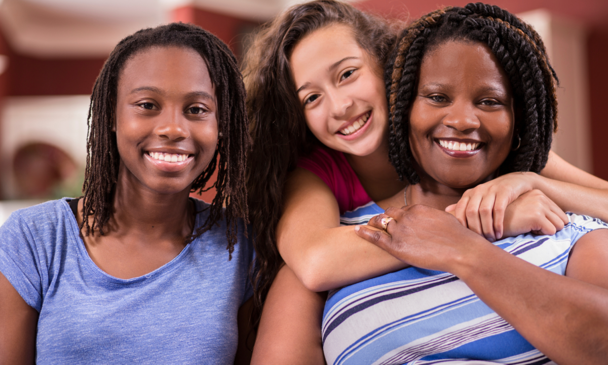 A woman and two teenager girls smile