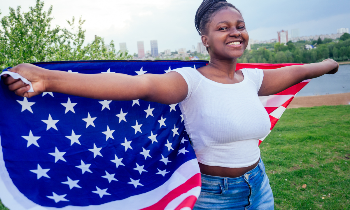 Teenage girl holding US flag behind her